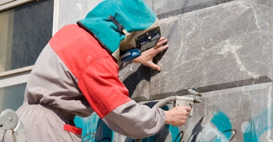 man in hood spraying graffiti